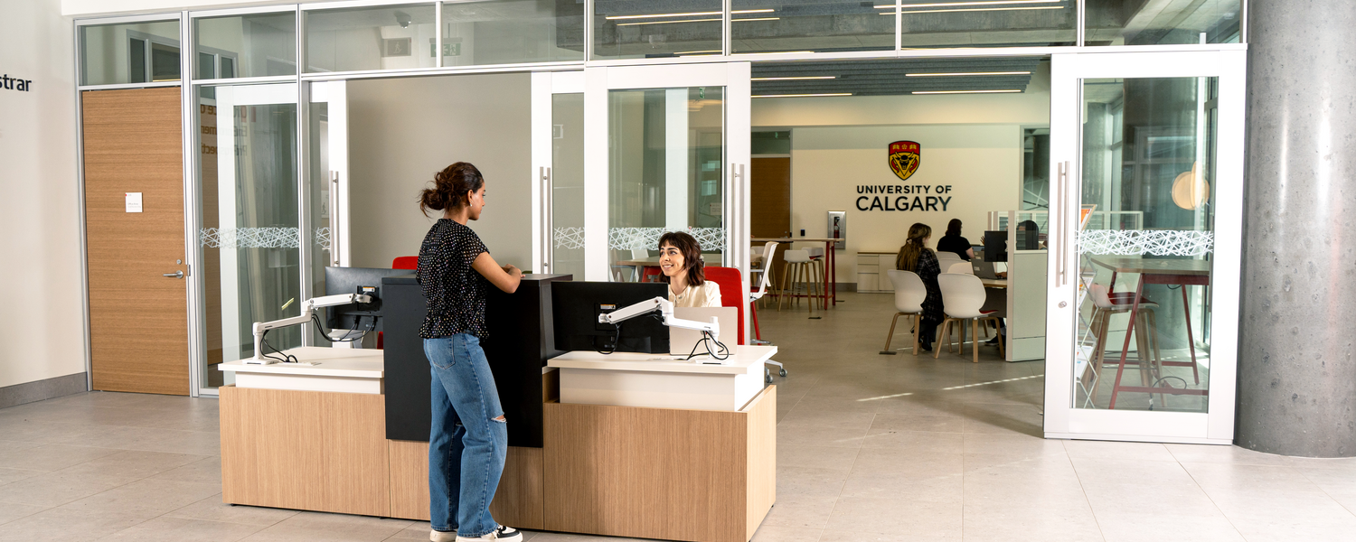 A female student stands at the reception desk of Enrolment Services 