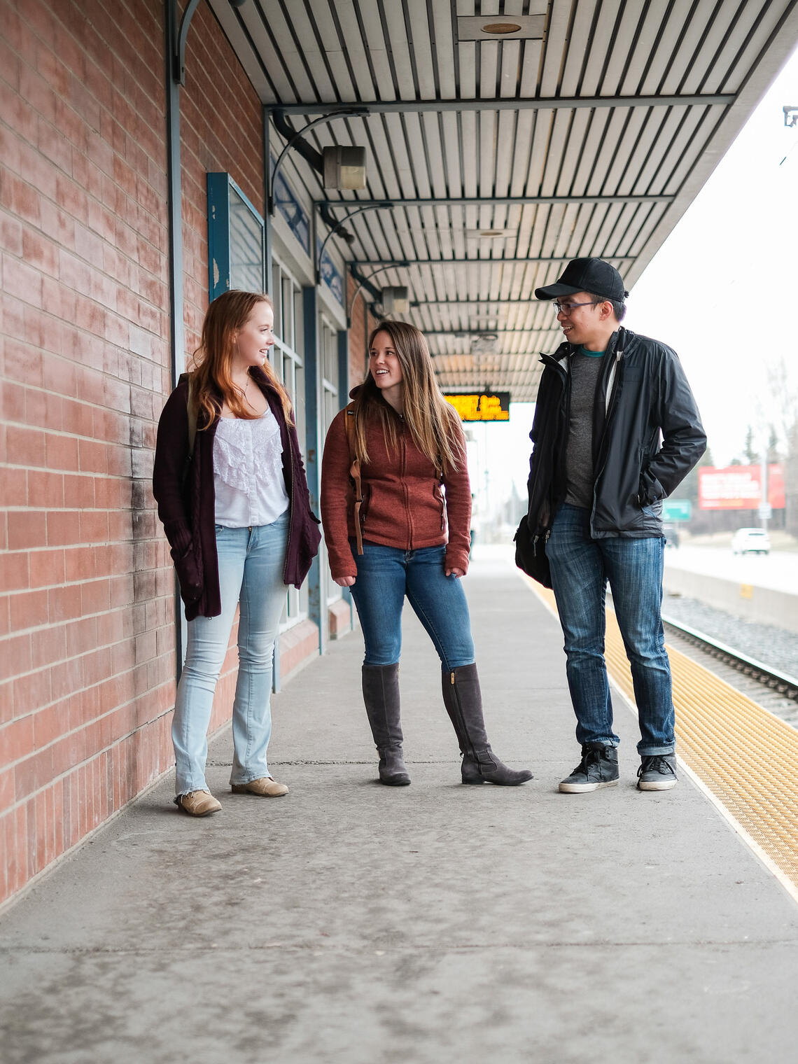 Three students stand on the University Station platform.