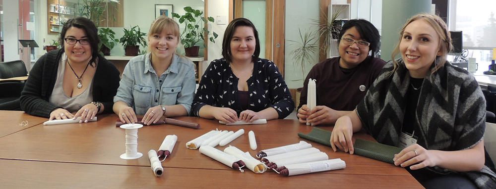 three students sit around a table with candles in front of them