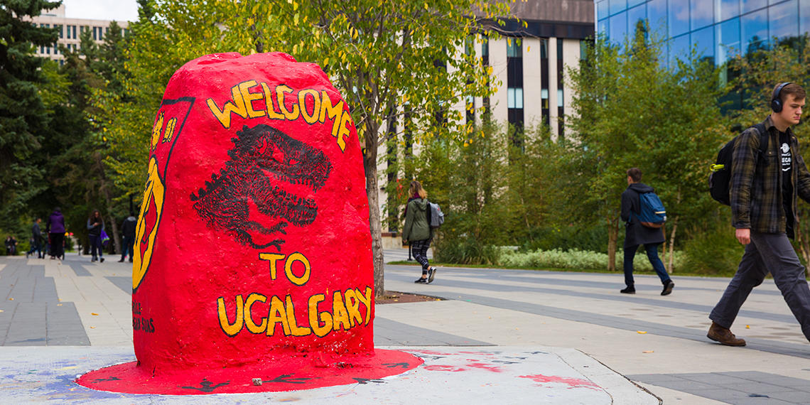 Rock with students walking around a campus