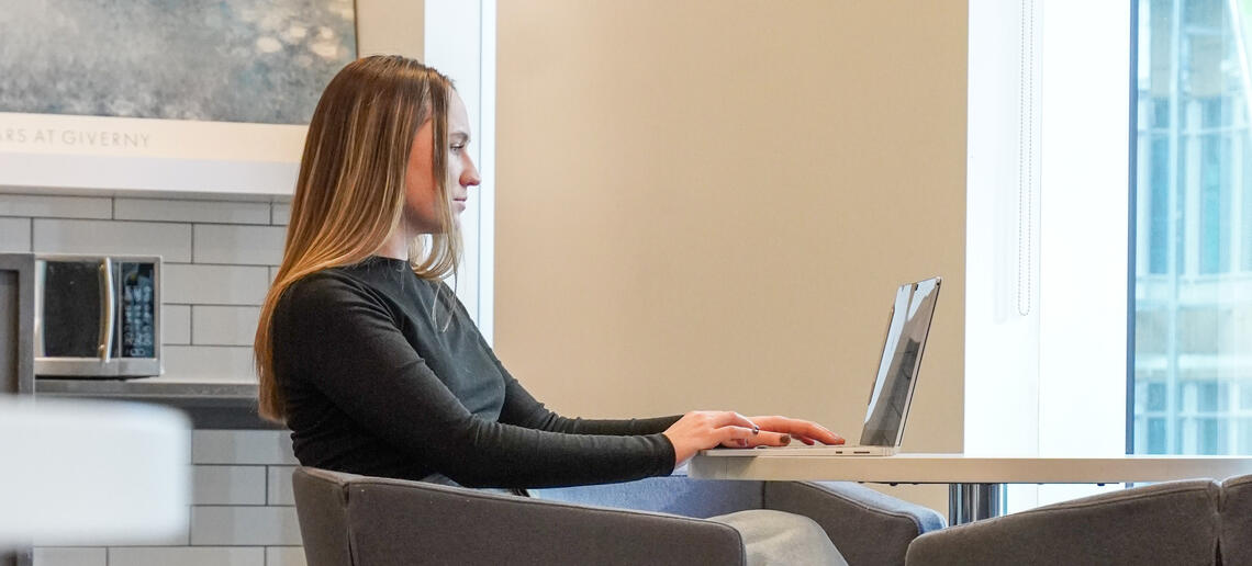 A student works on a laptop while seated in a study space