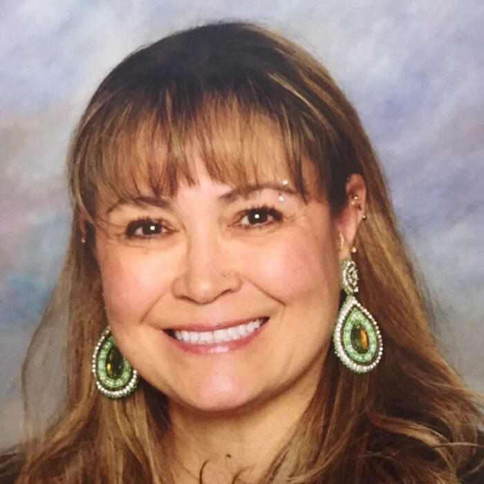 A woman with bangs wearing beaded earrings