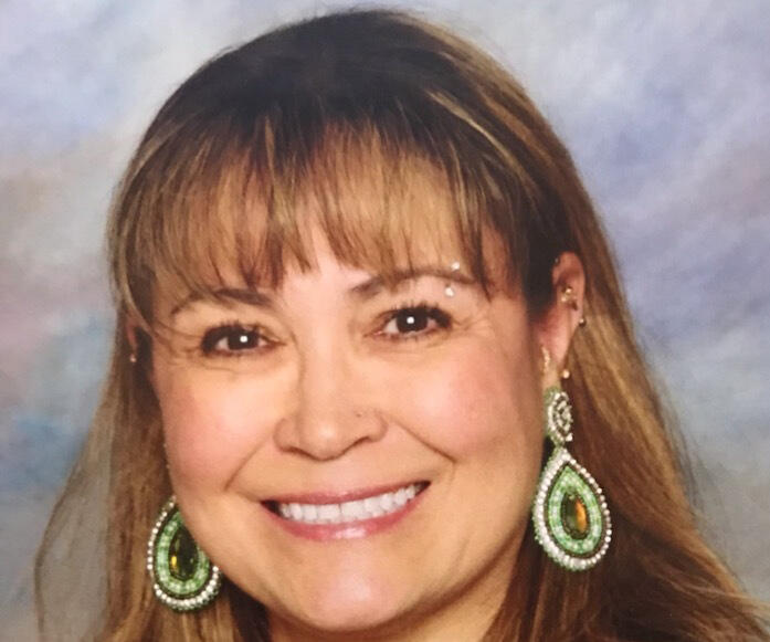 A woman with brown hair and beaded earrings