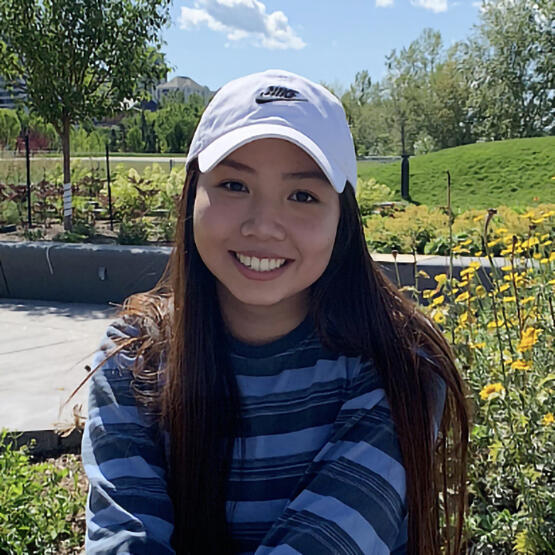 A woman in a baseball cap sits in front of flowers