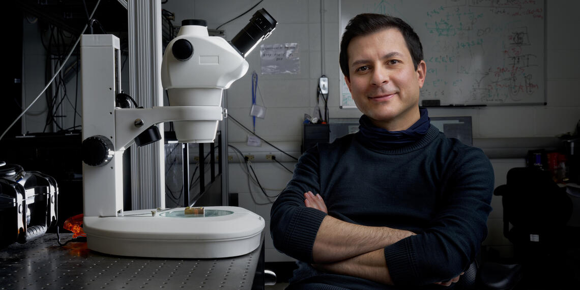 A man sitting in a lab next to a microscope