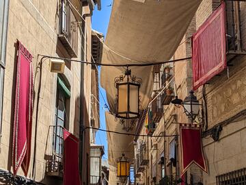 Looking up between two buildings with medieval style lantern & tapestry