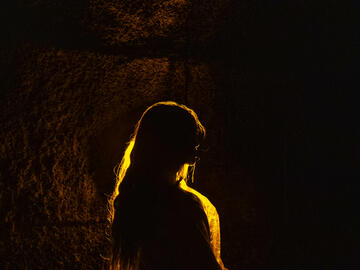 Silhouette of a person with long hair in a dark cave