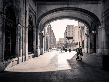Looking down a city street with old arched windows and a modern sculpture
