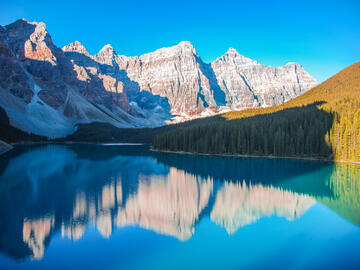 Clear wide lake reflecting the mountains and blue sky