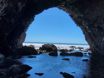 Looking out from a round cave entrance towards crystal blue ocean