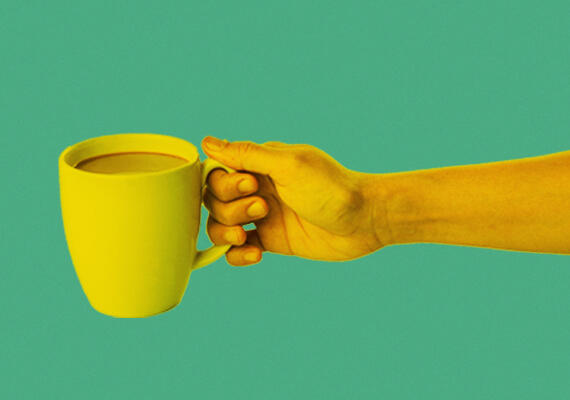 A hand holding a coffee cup against a green background