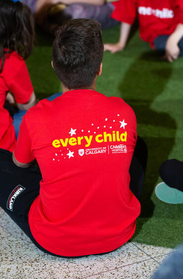 Kids in red t-shirts sitting on a green carpet