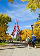 Students walking on pathway towards the UCalgary Zipper artwork