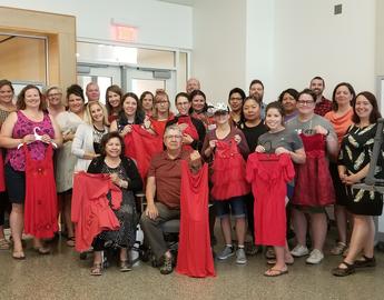 Large group of people, some holding red dresses (ii’ taa’poh’to’p Indigenous UCalgary)