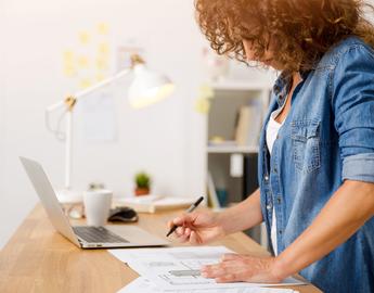 Middle age woman at the office working on with a laptop by Ikostudio