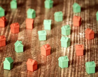 Red and green plastic toy houses on a wooden background.