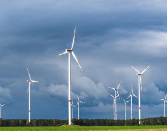 Wind turbines in open terrain on windy days with dark clouds in the sky. Alternative power generation. by Daniela Baumann