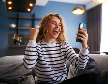 A person with blonde hair happy on their phone.