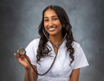 woman in white scrubs, holding a stethascope